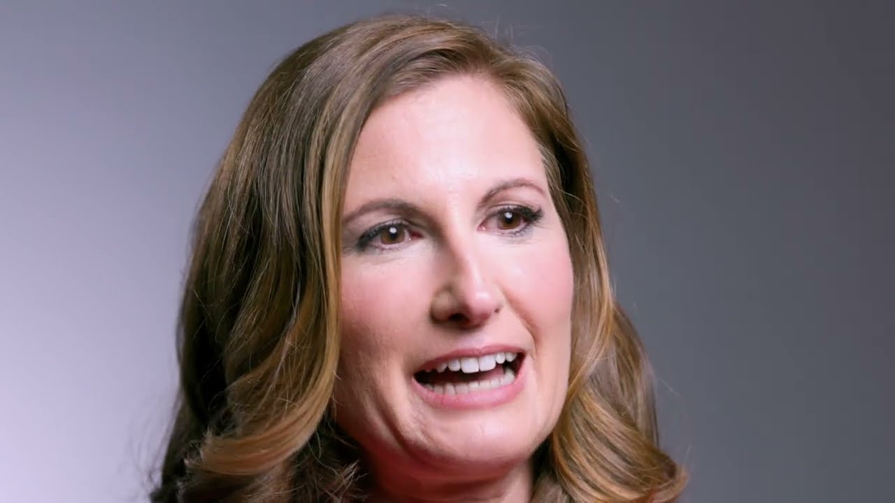 a woman with brown hair and a pink shirt