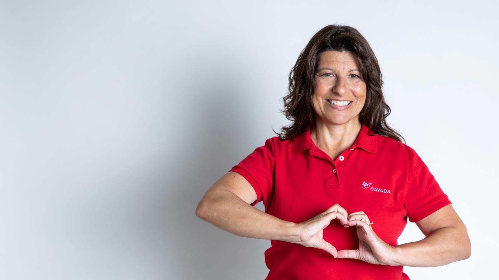 a woman in a red shirt making a heart with her hands