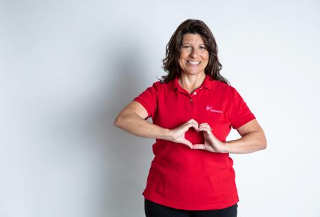 a woman in a red shirt making a heart with her hands