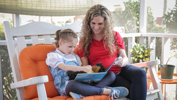a woman and a child sitting on a bench reading a book