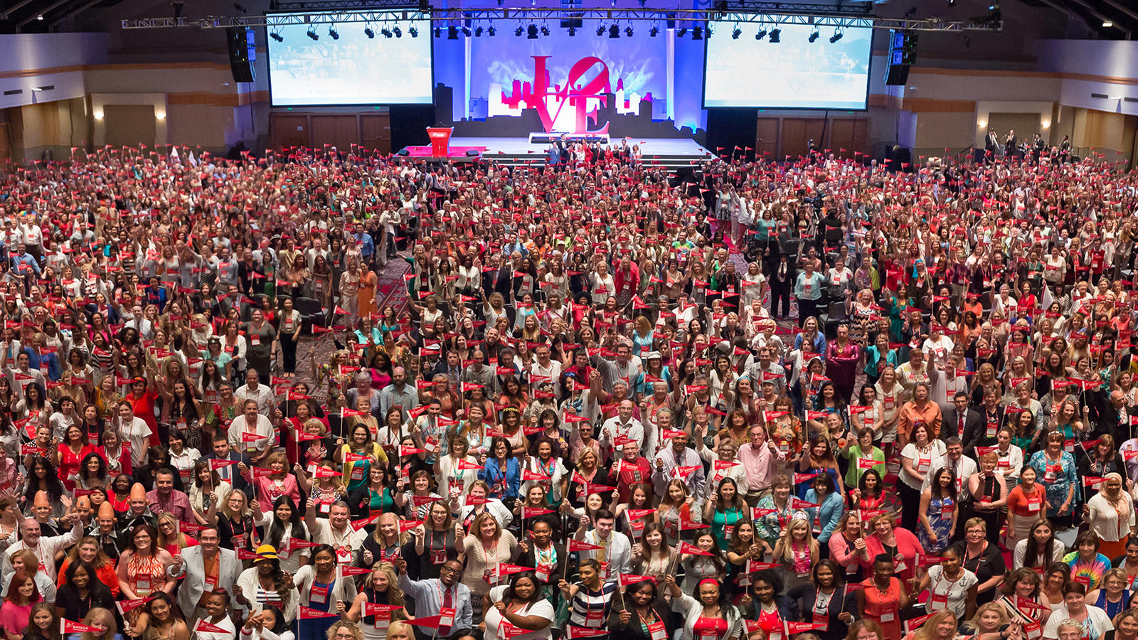 a large group of people holding red ribbons