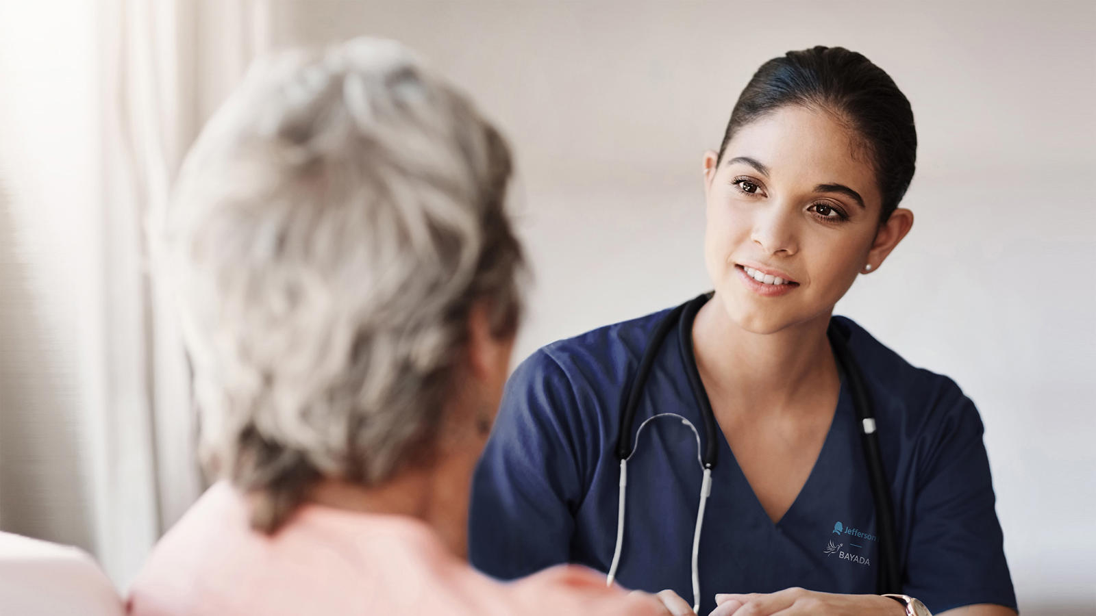 a woman in blue scrubs talking to a patient