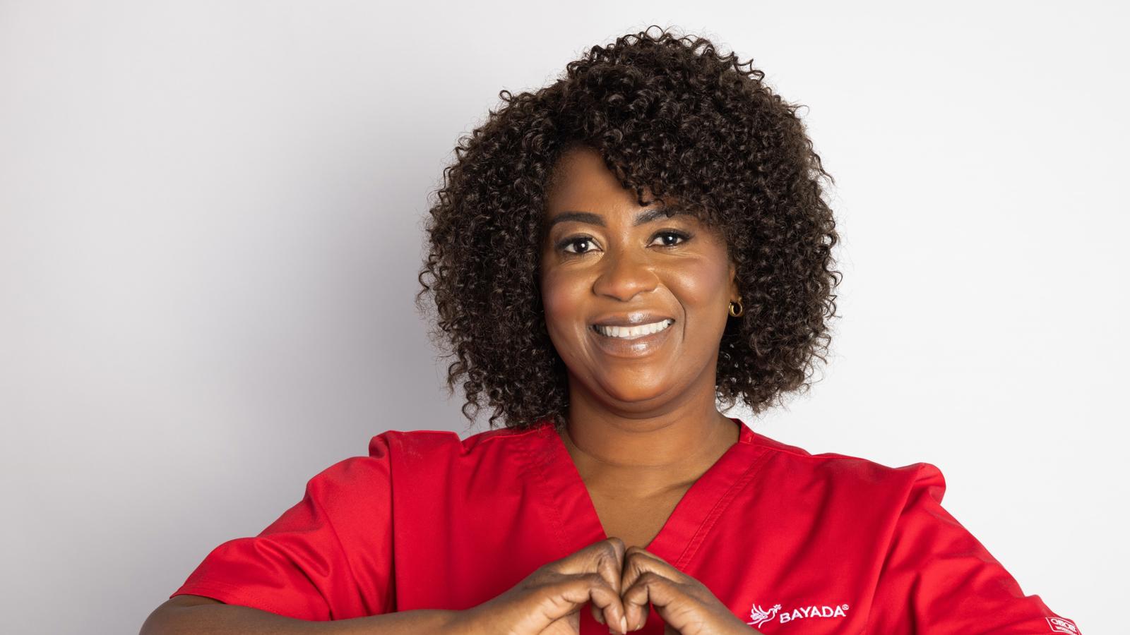 a woman in a red scrubs making a heart with her hands